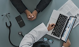 Arzt und Patient im Gespräch vor Computerbildschirm