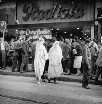 Zwei verschleierte Frauen vor einer Menschenmenge, im Hintergrund ein Kino.